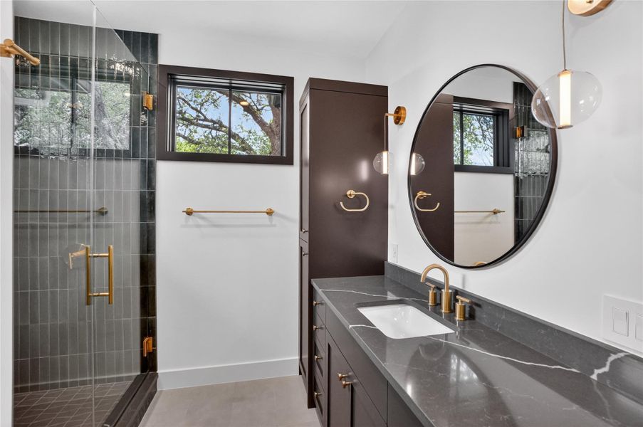 Luxurious bathroom showcasing a sleek vanity, an expansive shower, and chic fixtures.