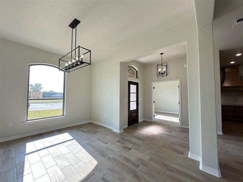 Unfurnished dining area with a chandelier and wood finish floors