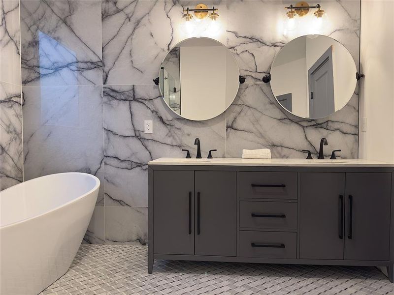 Bathroom featuring tile walls, a tub, tile patterned floors, and double sink vanity