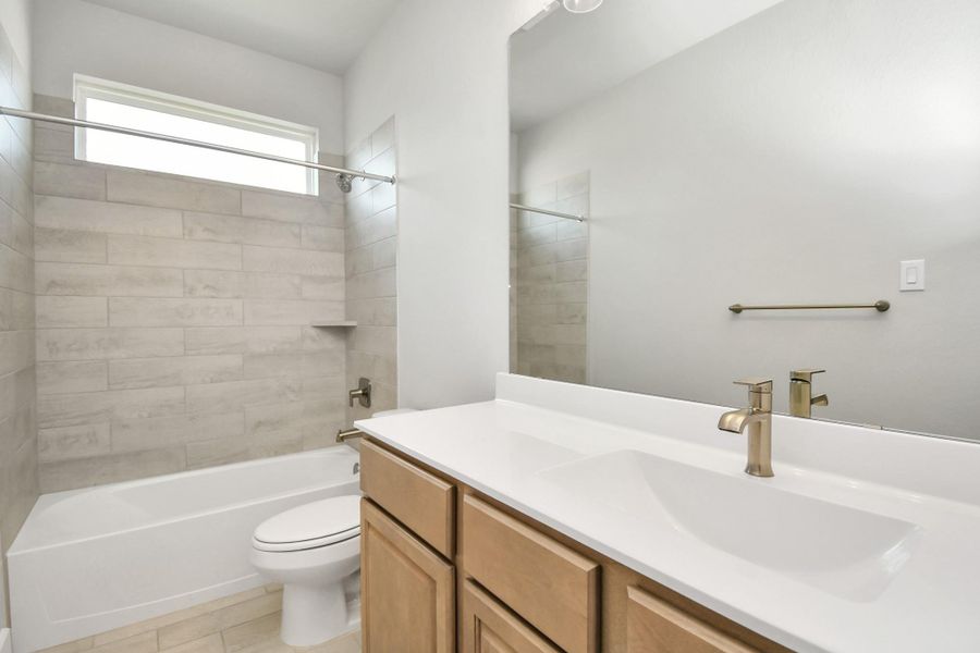 Secondary bath features tile flooring, bath/shower combo with tile surround, light stained wood cabinets, beautiful light countertop. Secondary bath features tile flooring, bath/shower combo with tile surround, light stained wood cabinets, beautiful light countertop.
