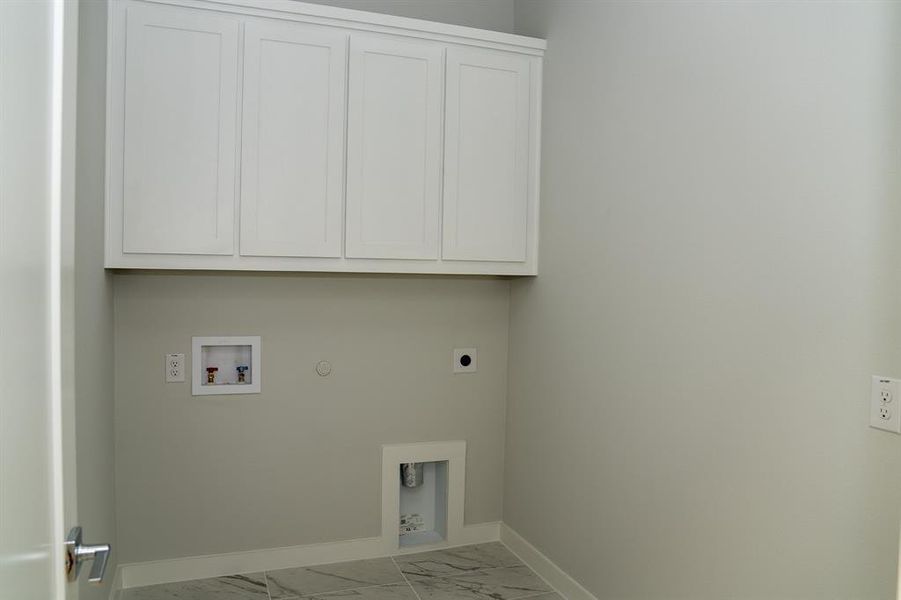 Laundry area featuring white shaker-style cabinetry, light gray walls, and tile flooring Laundry area featuring white shaker-style cabinetry, light gray walls, and tile flooring