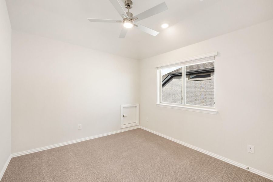 Empty bedroom with carpet flooring, ceiling fan, and a single window with white walls Empty bedroom with carpet flooring, ceiling fan, and a single window with white walls
