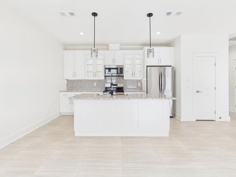 Kitchen with white cabinets, pendant lighting, light stone counters, tasteful backsplash, and appliances with stainless steel finishes Kitchen with white cabinets, pendant lighting, light stone counters, tasteful backsplash, and appliances with stainless steel finishes