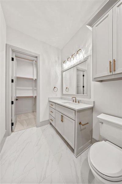 Bathroom featuring vanity, light marble finish flooring, and a walk in closet Bathroom featuring vanity, light marble finish flooring, and a walk in closet