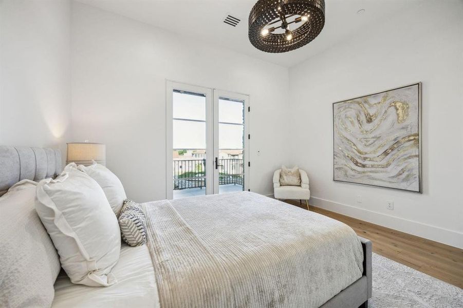 Guest suite on main level with access to balcony, French doos, wood finished floors, and baseboards Guest suite on main level with access to balcony, French doos, wood finished floors, and baseboards