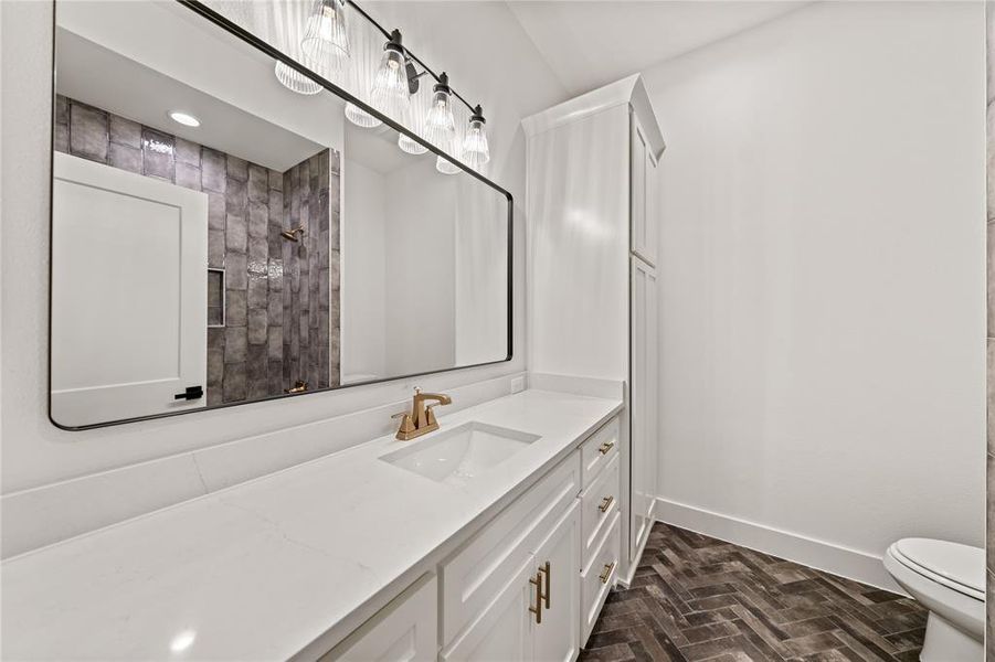 Modern vanity featuring white cabinetry, gold-finish hardware, a single undermount sink, and a white countertop