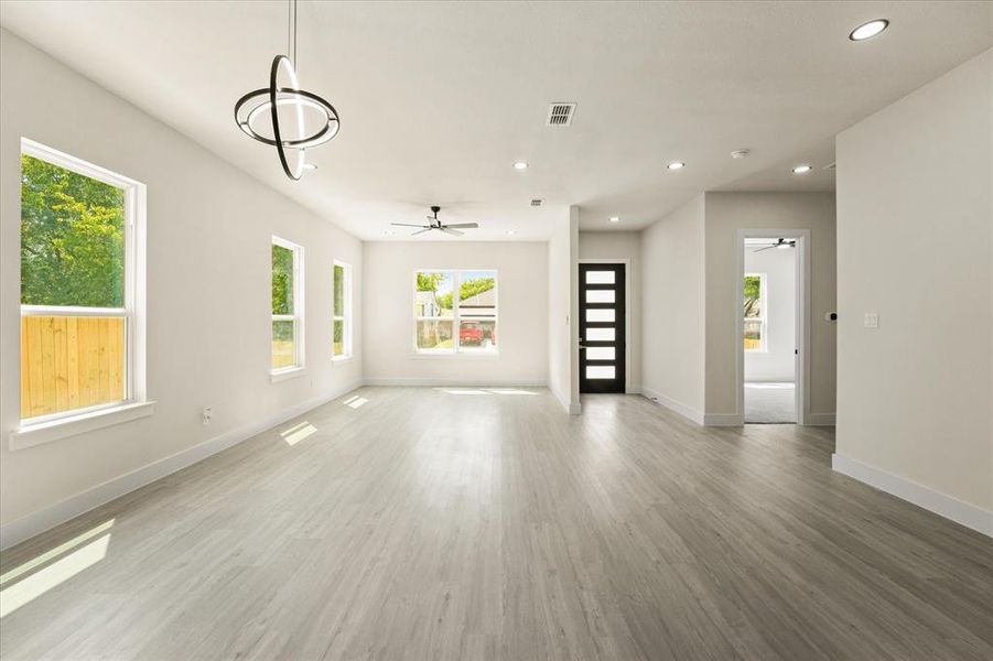 Unfurnished living room with plenty of natural light, light wood-style floors, recessed lighting, and a ceiling fan Unfurnished living room with plenty of natural light, light wood-style floors, recessed lighting, and a ceiling fan