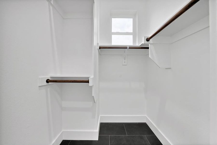 Built-in closet system featuring multiple hanging rods, overhead shelving, and a window for natural illumination