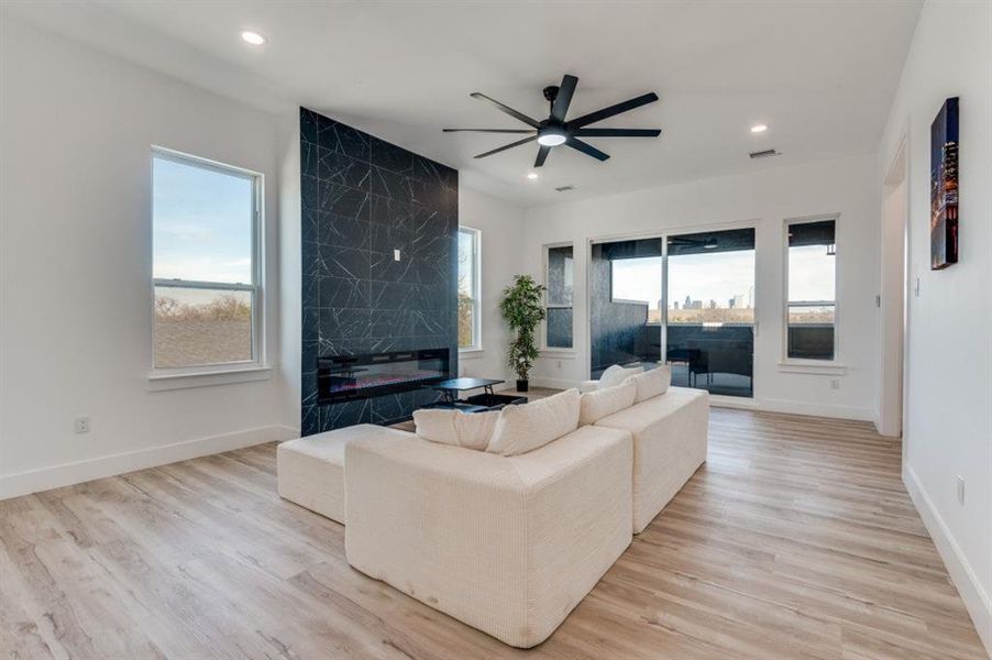 Skyline view Living room featuring light wood-type flooring, a ceiling fan, and a high end fireplace