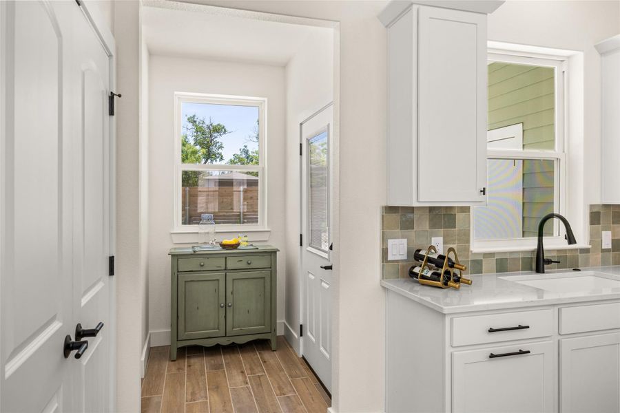 A well-lit kitchen area features a white cabinet, a window with exterior view, and wood-look flooring.