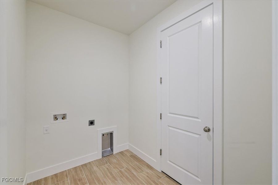 Washroom with wood finish floors, hookup for an electric dryer, and washer hookup