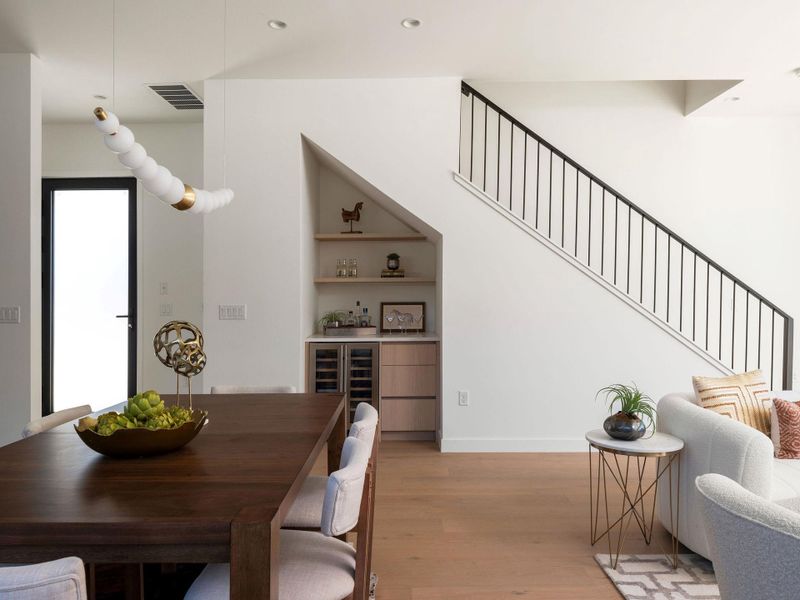 Dining room with light wood-style flooring, beverage cooler, and built in features