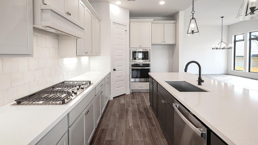 Kitchen featuring wood finish floors, appliances with stainless steel finishes, decorative backsplash, recessed lighting, and under cabinet range hood