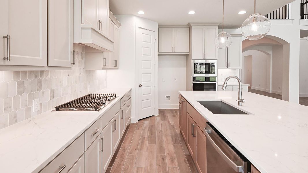 Kitchen featuring appliances with stainless steel finishes, a sink, light wood-style flooring, recessed lighting, and light stone counters Kitchen featuring appliances with stainless steel finishes, a sink, light wood-style flooring, recessed lighting, and light stone counters