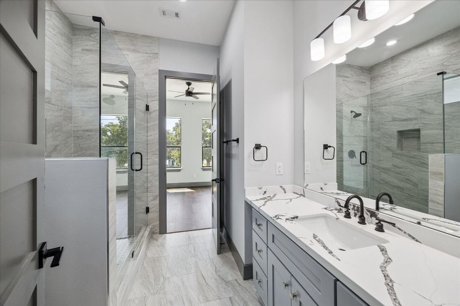 A spacious vanity, and a glass-enclosed shower define this well-appointed secondary bathroom. Thoughtful finishes and durable materials balance style with everyday function.