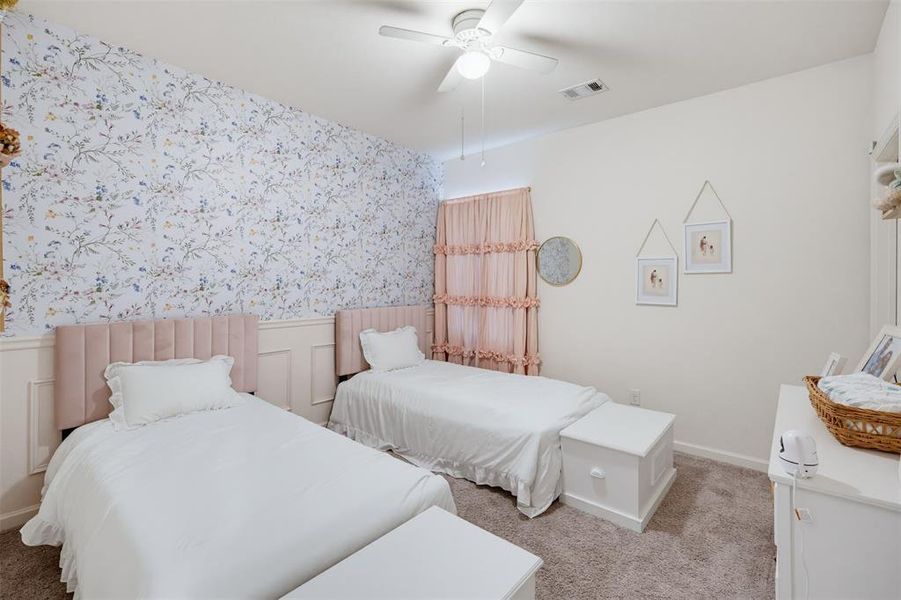 Room featuring a floral accent wall, wainscoting, and carpeted flooring