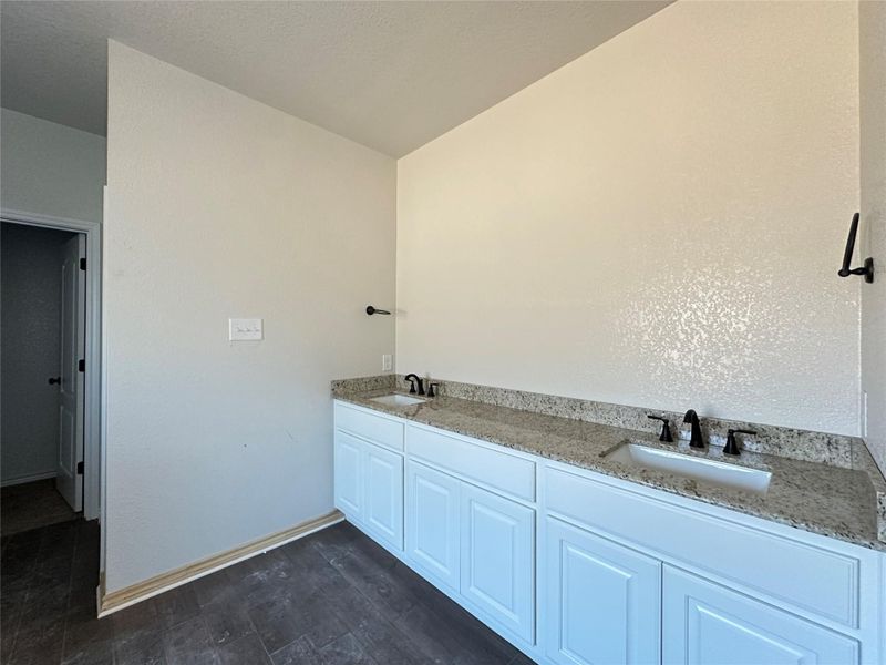 Full bathroom with double vanity and dark wood-type flooring