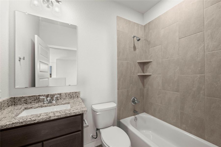 A well-appointed bathroom features a deep soaking tub and a sleek vanity with granite counters.