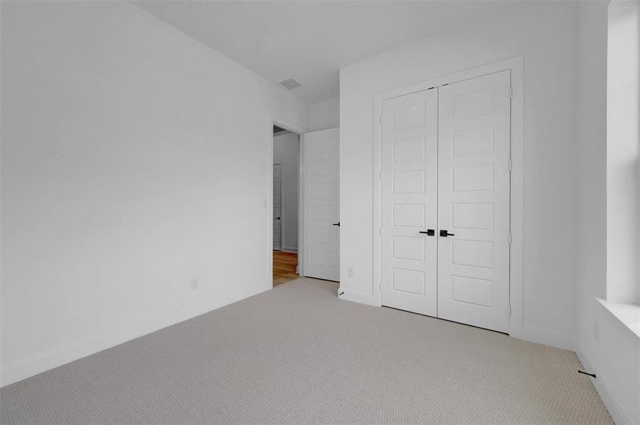 Unfurnished bedroom with light colored carpet and a closet