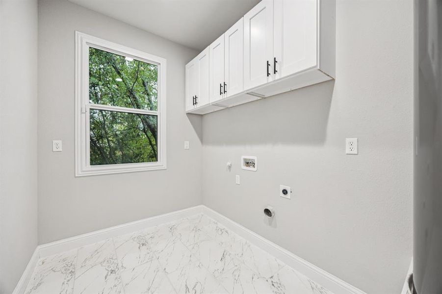 Washroom featuring cabinet space, gas dryer hookup, light marble finish flooring, electric dryer hookup, and washer hookup