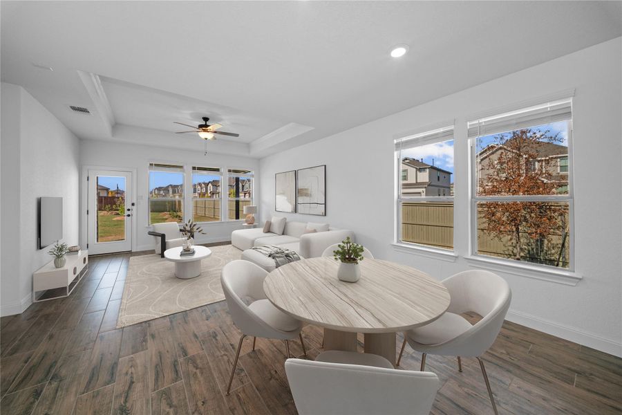 Dining room with a raised ceiling, dark wood-style floors, and a ceiling fan Dining room with a raised ceiling, dark wood-style floors, and a ceiling fan