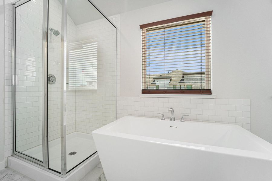 Freestanding tub with separate glass-enclosed shower and tile surround.