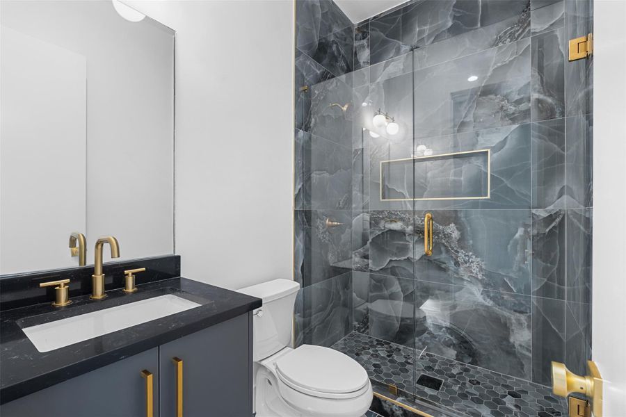 Contemporary bathroom featuring a dark vanity with a white rectangular sink and gold fixtures