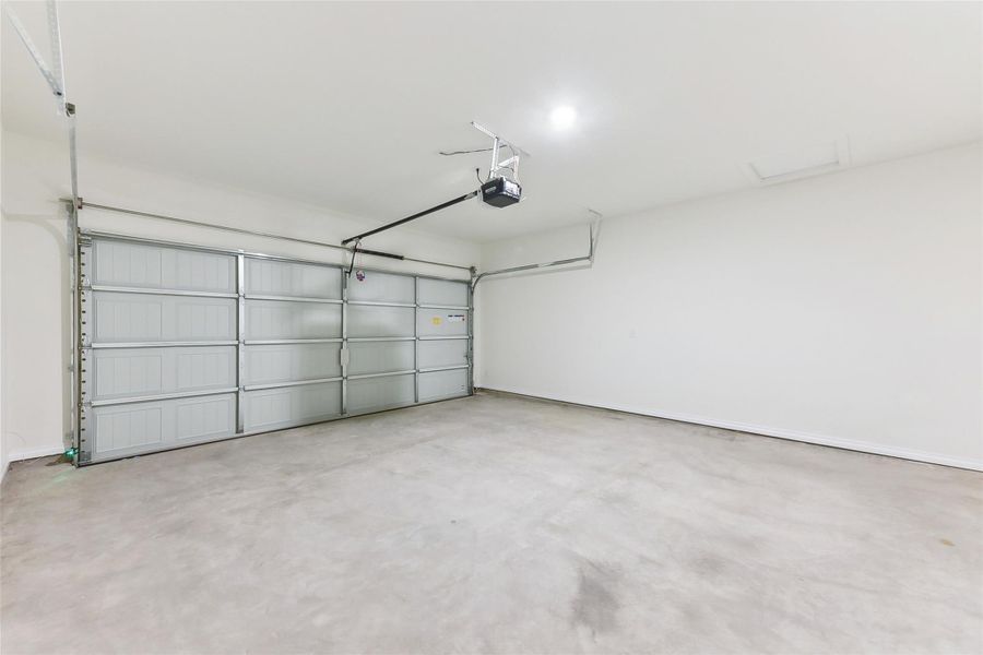 Garage featuring baseboards and a garage door opener Garage featuring baseboards and a garage door opener