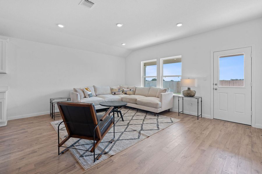 Living room with light wood finished floors, recessed lighting, and lofted ceiling Living room with light wood finished floors, recessed lighting, and lofted ceiling