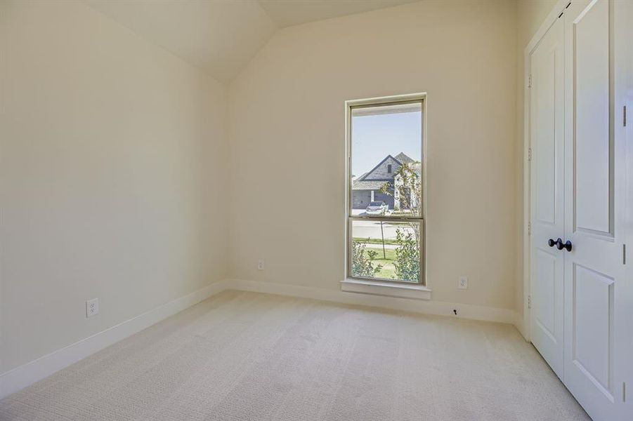 Unfurnished bedroom with light carpet, a closet, and vaulted ceiling