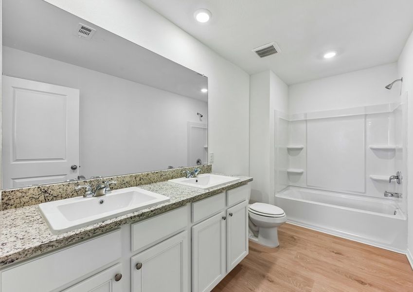 Secondary bathroom featuring a double vanity with granite countertop and a tub/shower combination.