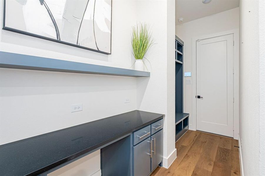 Bar area featuring light wood-type flooring, dark stone counters, and open shelves