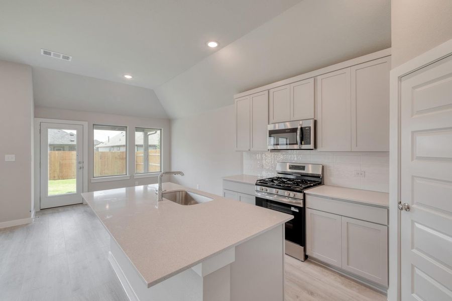 A well-lit kitchen with sleek countertops and modern appliances, perfect for culinary endeavors. A well-lit kitchen with sleek countertops and modern appliances, perfect for culinary endeavors.