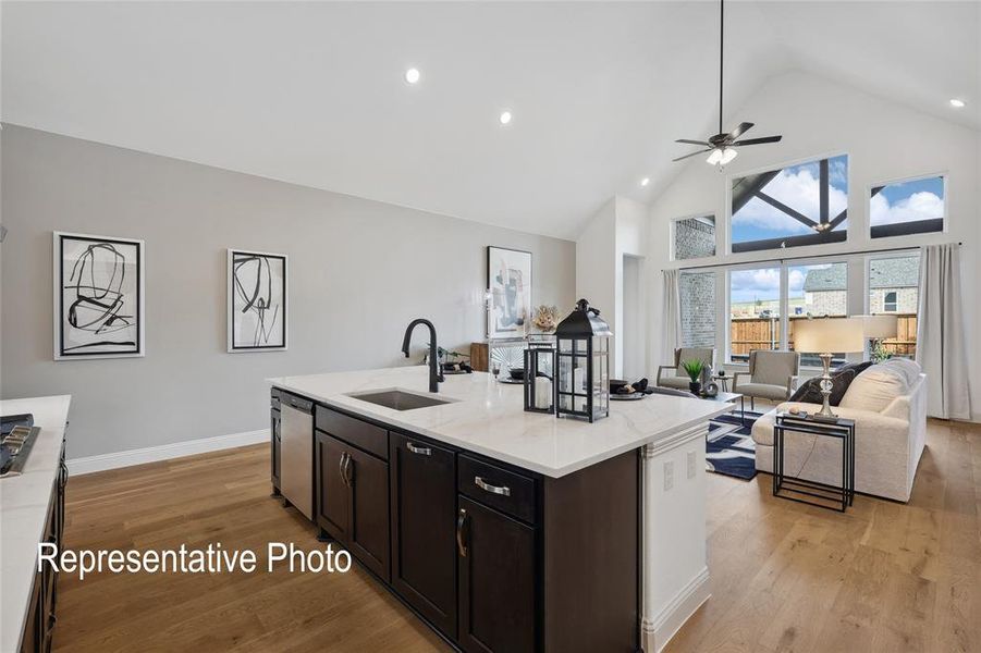Open-concept living area featuring a kitchen island with sink, dark cabinetry, and light countertops