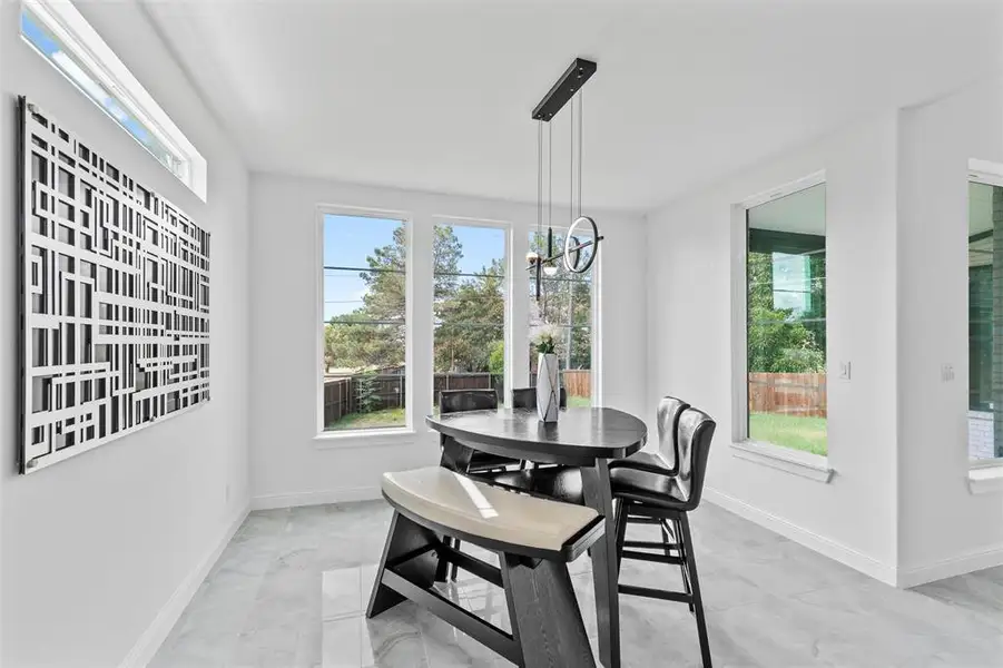Bright dining area featuring large windows, a transom window, and light-toned tile flooring