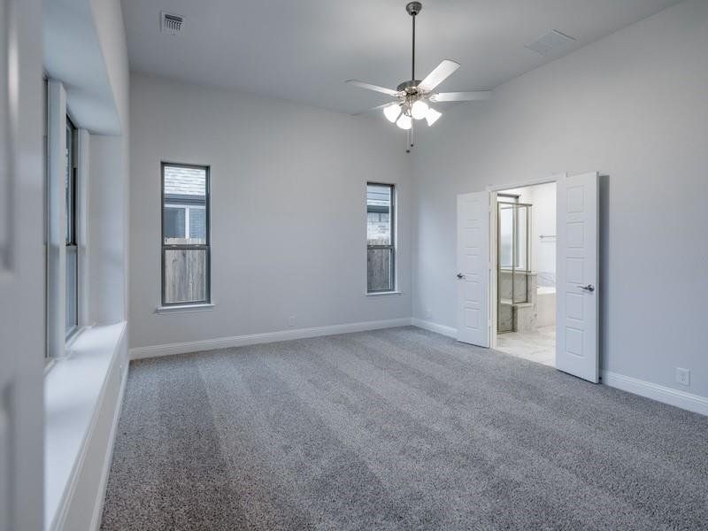 Unfurnished bedroom featuring multiple windows, lofted ceiling, light carpet, and ceiling fan