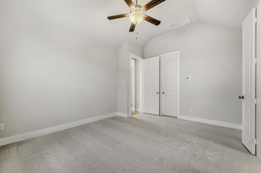 Unfurnished bedroom featuring light colored carpet, vaulted ceiling, ceiling fan, and a closet