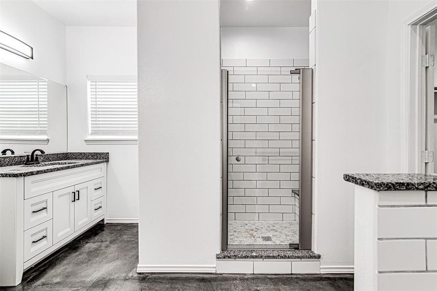 Bathroom with vanity, concrete floors, and a shower with shower door