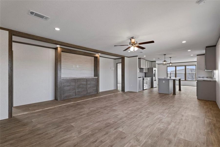 Unfurnished living room featuring dark wood-style flooring, ceiling fan, and recessed lighting