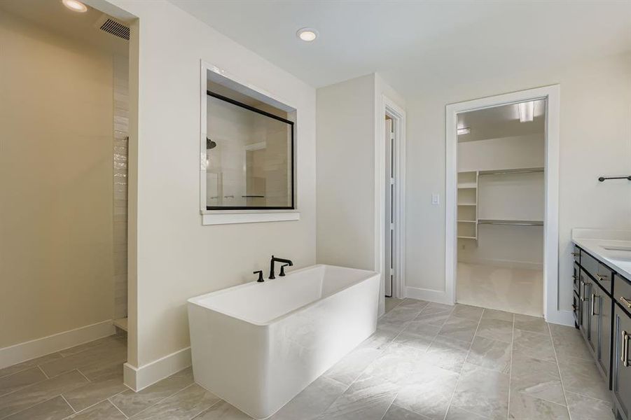 Full bathroom with a spacious closet, a freestanding tub, recessed lighting, vanity, and walk in shower