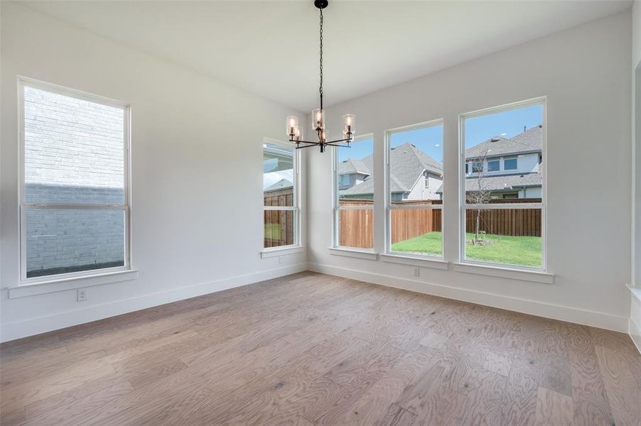 Unfurnished dining area featuring hardwood / wood-style flooring and an inviting chandelier