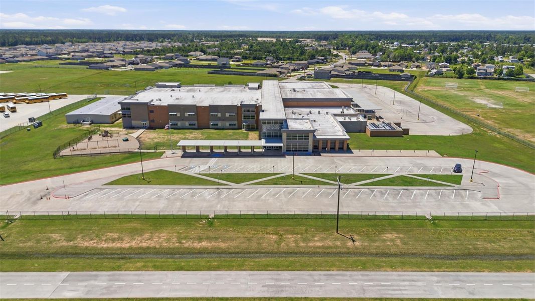 School building with ample parking and sports fields, set in a suburban neighborhood. Ideal for families seeking proximity to educational facilities.