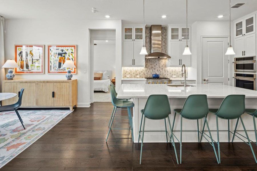 Kitchen with visible vents, dark wood-style flooring, a sink, decorative backsplash, and wall chimney range hood