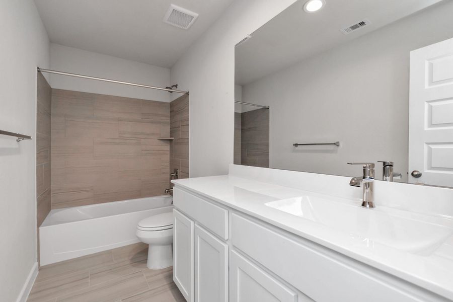 Experience sophistication in the secondary bathroom, where tile flooring complements a bath/shower combo with tile surround. Sample photo of completed home with similar floor plan. Actual colors and selections may vary.