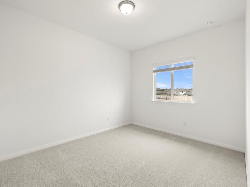 An airy bedroom with a soft carpet, bathed in light from a large window.