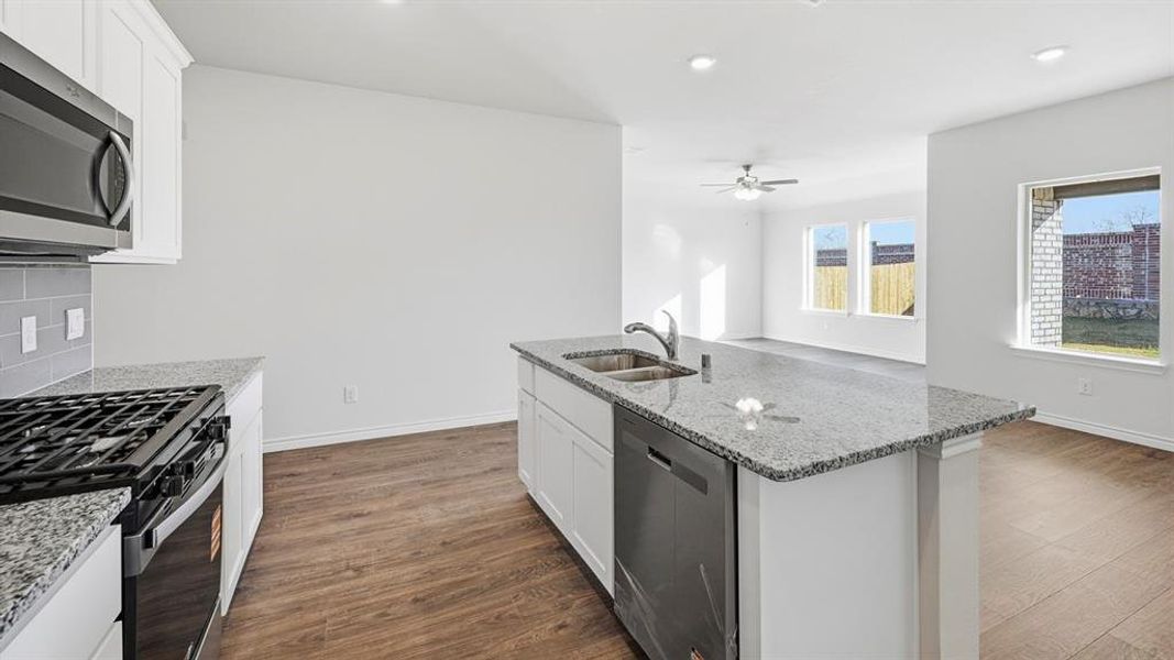 Kitchen with a center island with sink, stainless steel appliances, white cabinets, light stone counters, and recessed lighting Kitchen with a center island with sink, stainless steel appliances, white cabinets, light stone counters, and recessed lighting