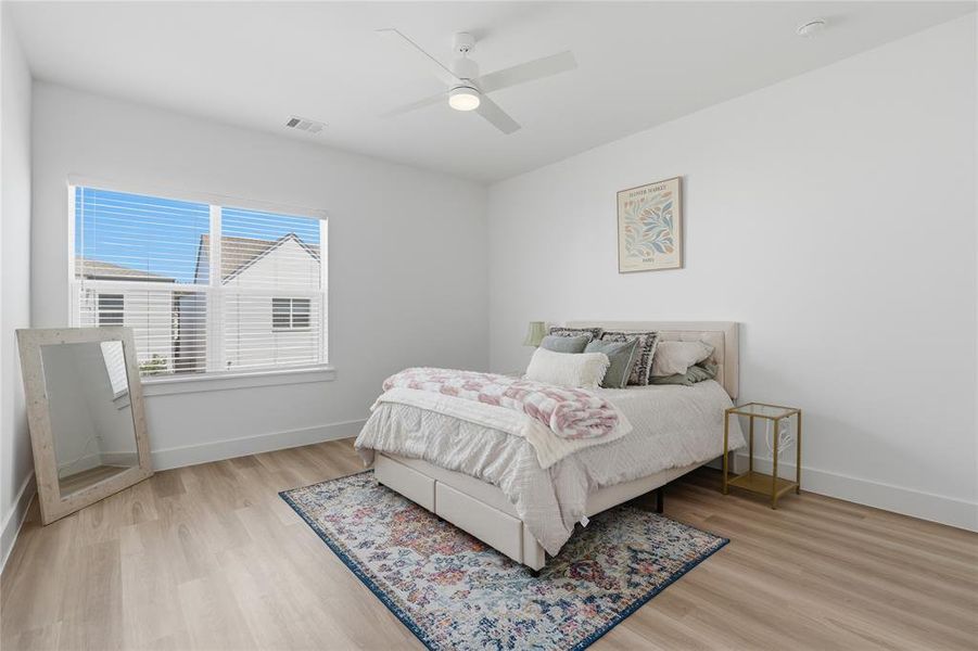 Bright room featuring a large window with white blinds, wood-finish flooring, white walls, and a ceiling fan with integrated lighting