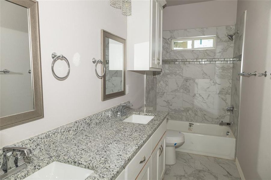 Full bathroom with tiled shower / bath, vanity, and toilet