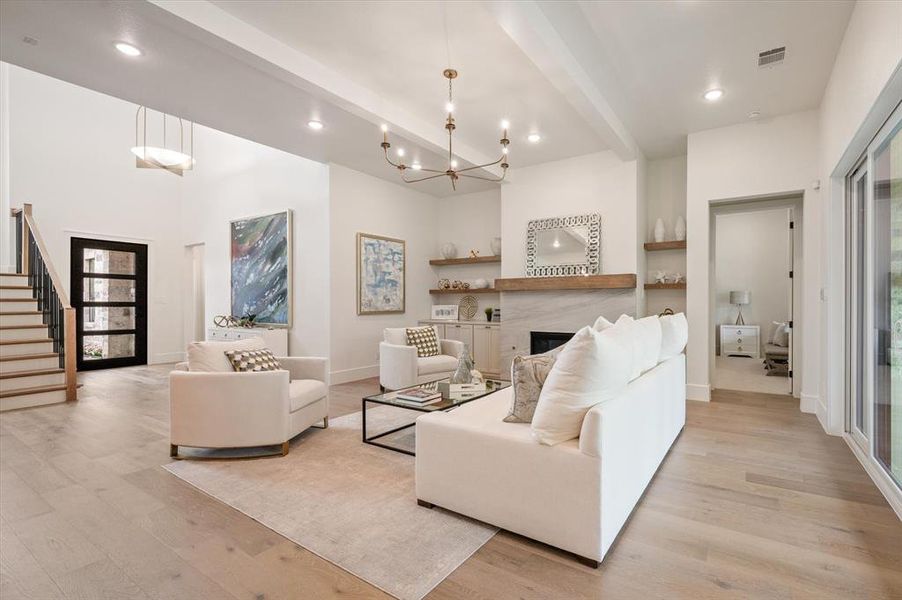 Living room with an inviting chandelier, light wood-type flooring, and beam ceiling