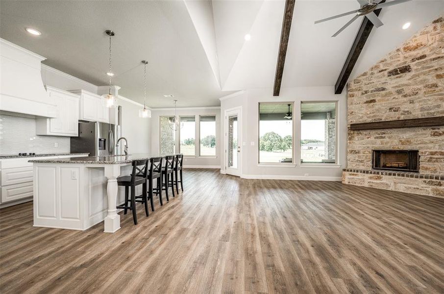 Kitchen featuring beamed ceiling, custom exhaust hood, stainless steel refrigerator with ice dispenser, hardwood / wood-style flooring, and a spacious island